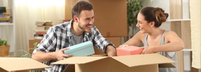 Smiling couple packing moving boxes