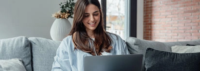 Smiling woman on couch with laptop